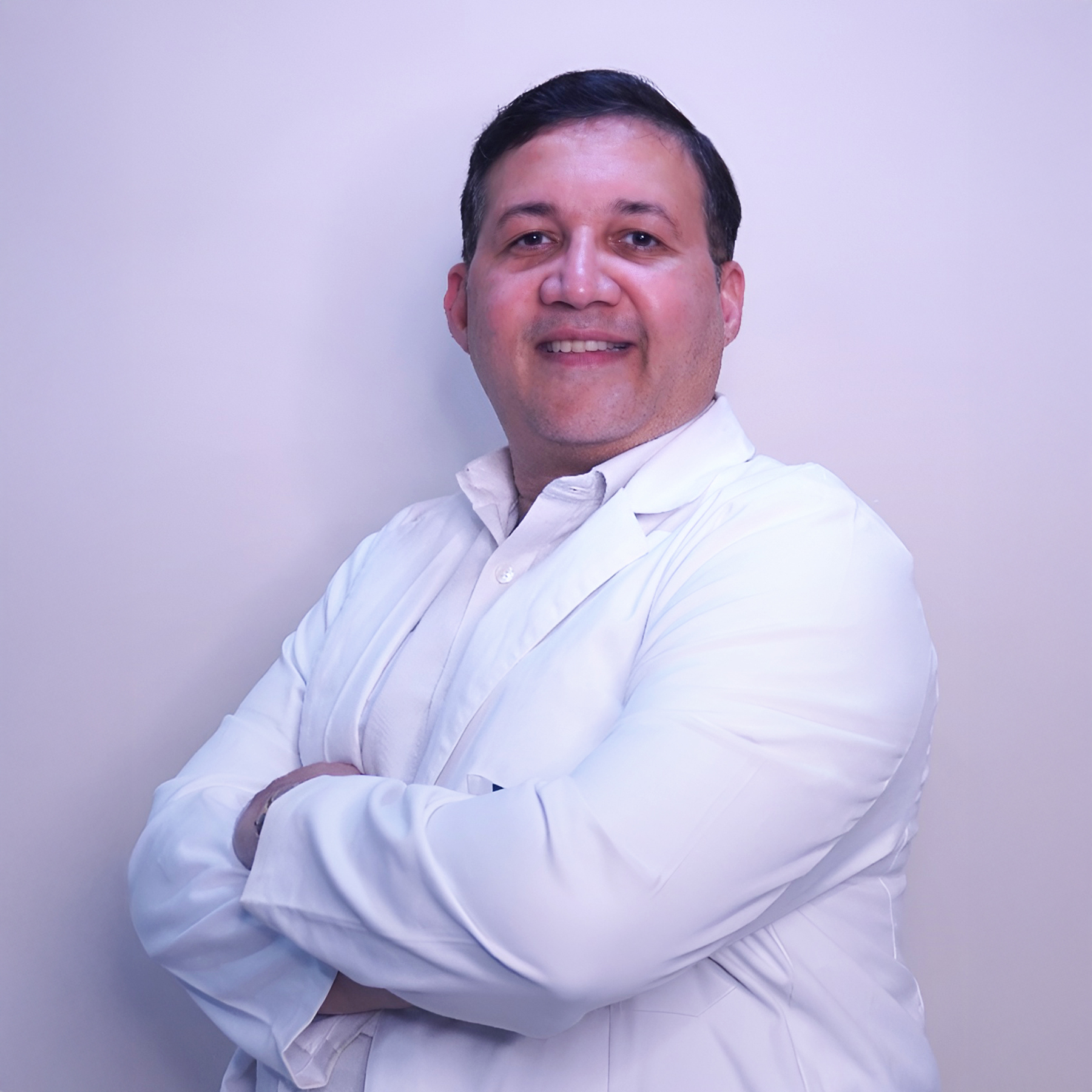 Portrait of Dr. T. Dinesh Singh, a male ENT surgeon wearing a white coat and stethoscope, smiling, vertical rectangle photo