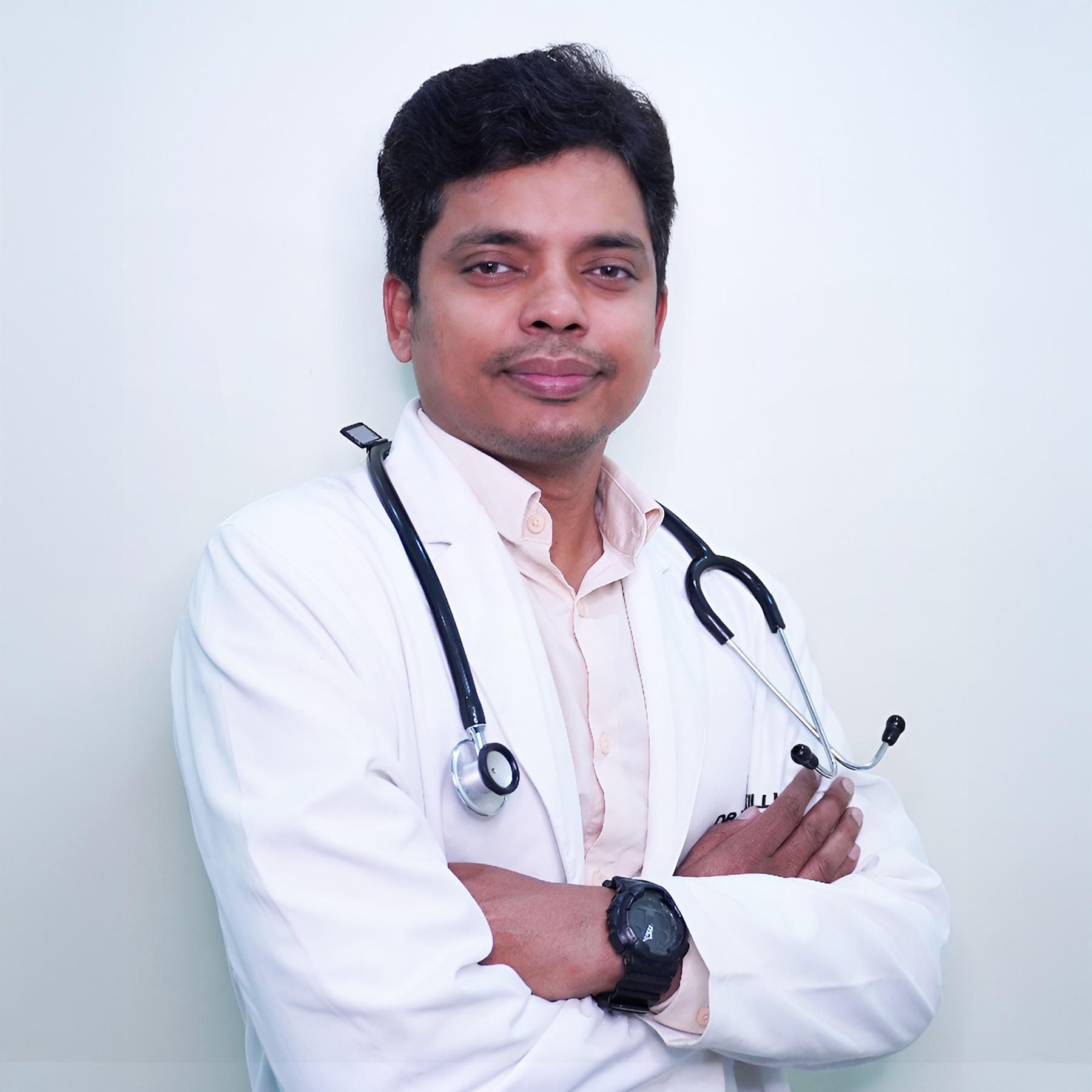 Portrait of Dr. Naresh Killi, a male general physician, smiling and wearing a white coat, vertical rectangle photo